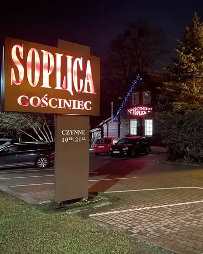 Podświetlony szyld Soplica Gościniec wieczorem